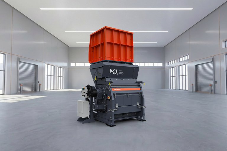 M&J F140 hydraulic fine-shredder with orange feed hopper, standing in a workshop